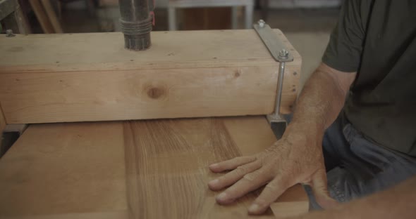 Carpenter pulls and files back a wooden plank