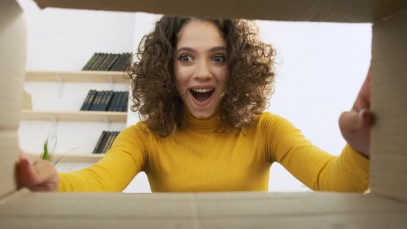 Young Surprised Woman Unpacking Opening Carton Box and Looking Inside alt