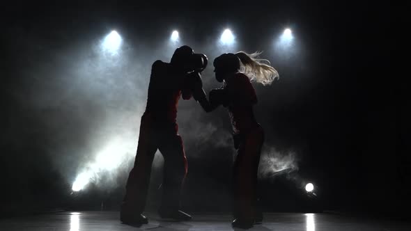 Girl Is Kicking a Guy with Their Sparring Kickboxing. Light From Behind. Smoke Background alt