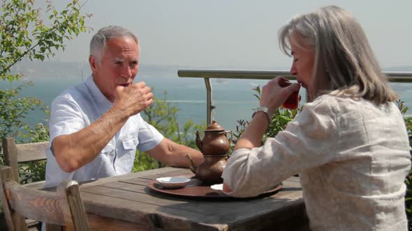 Couple drinking tea on terrace looking out over river Bosphorus, Turkey, Istanbul alt