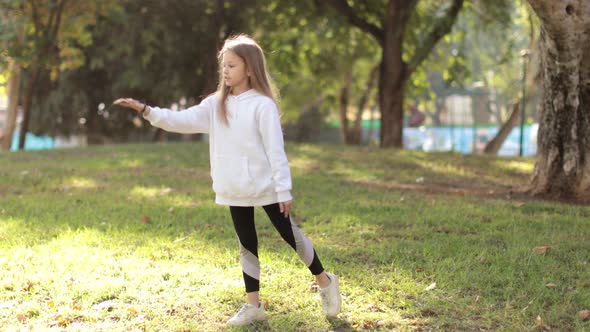 Little Girl Doing Exercises in the Park