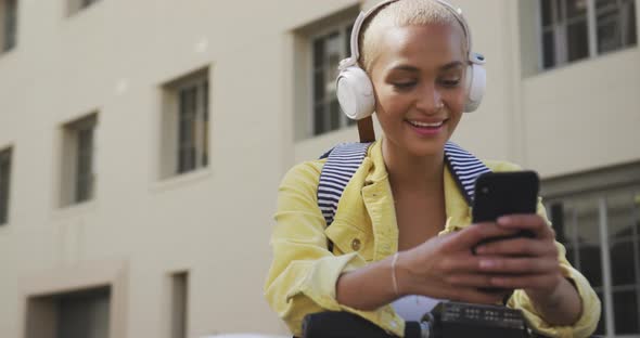 Mixed race woman listening music on the street on her e scooter alt