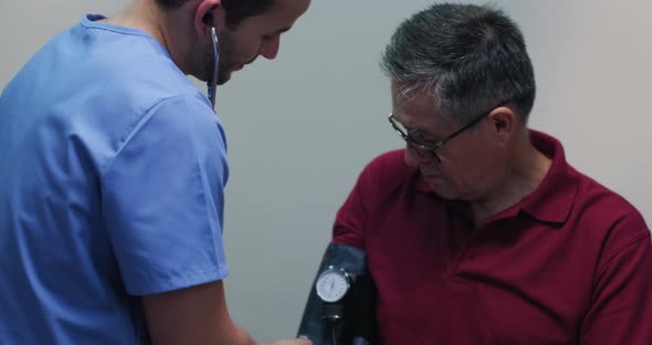 Slow Motion Portrait Nurse measuring high blood pressure of a senior hispanic man with stethoscope