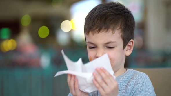 Portrait of Handsome Boy Wiping His Mouth with Napkin in Restaurant alt