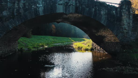 Old Dark Stone Bridge Situated Over Stream in Autumn Park alt