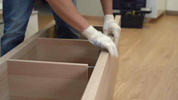 Male Hands Fix Wooden Panel in Bookcase
