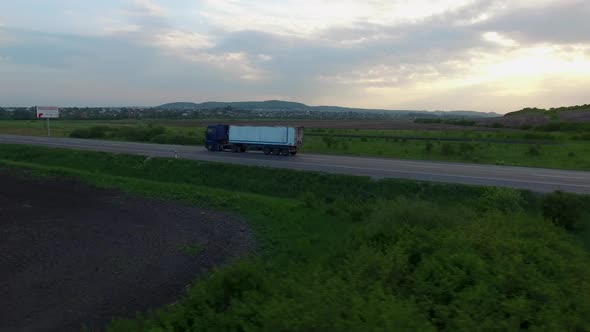 Aerial shot of truck driving a road benween fields.