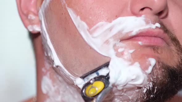 Young Man with a Safety Razor and Shaving Cream on His Face alt