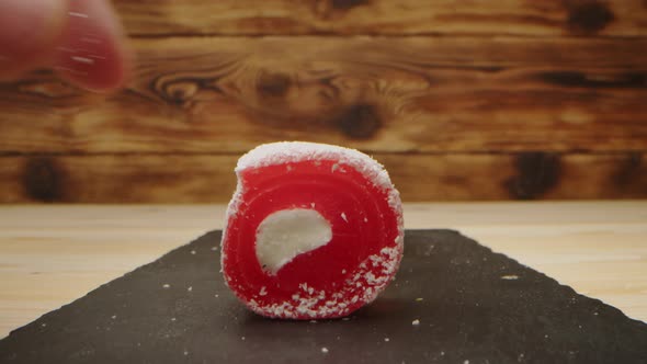 Hand Takes Eastern Sweets on Wooden Background Closeup