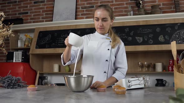Young Female Confectioner Pouring white Egg Cream in Bowl for Making Sour Cream alt