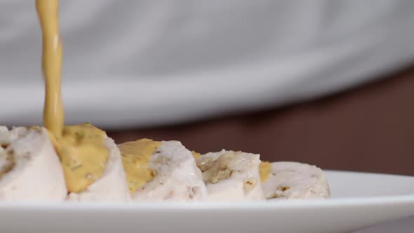 Cook Pours Sauce Over Chicken Roll alt