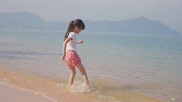Happy young cute Asian girl running on the beach then jumping on the sea with happiness on holiday. alt