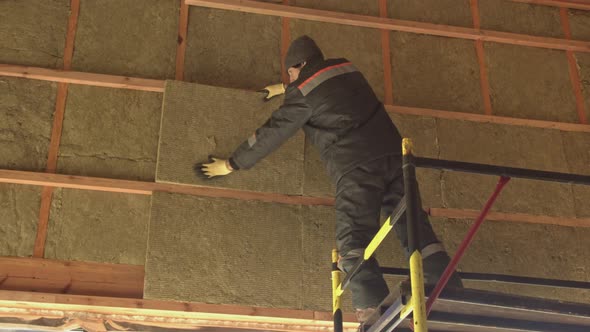 Man laying insulation at height 4K