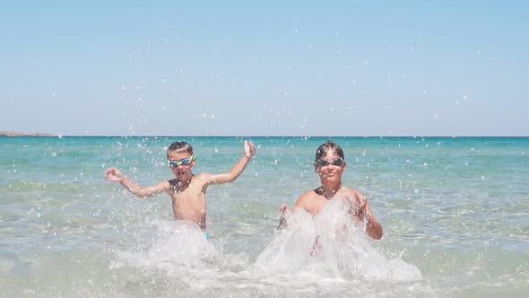 Children Play in the Purest Azure Sea on a Sunny Day Creating a Splashing Splashing Slowmotion Video