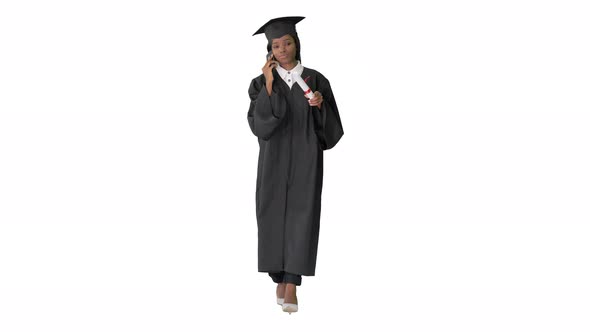 African American Female Student in Graduation Robe Talking on the Phone While Walking on White alt