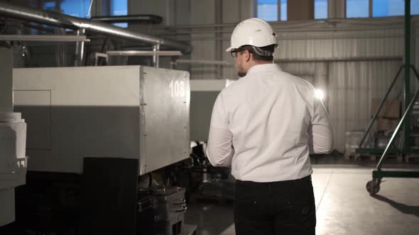 Engineer in Hard Hat is Walking Through Factory alt
