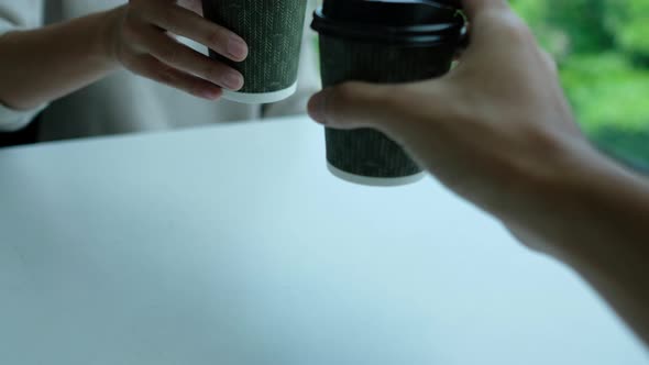 Closeup of couple people clinking coffee cups together in cafe