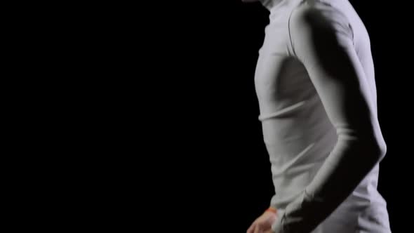 A Male Gymnast in White Does Acrobatic Stunts on a Black Background in Slow Motion alt