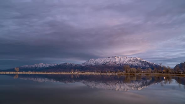 Time lapse of colorful sunrise reflecting in Utah Lake with snow capped mountain alt