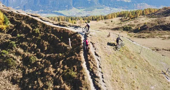 Aerial drone view of a group of mountain bikers on a singletrack trail. alt