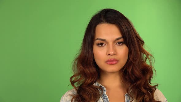 A Young Beautiful Caucasian Woman Looks Seriously at the Camera  Closeup  Green Screen Background