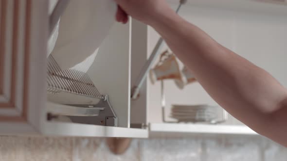 Man Pulls Out Two Plates From the Cabinet in the Kitchen Preparation for Dinner alt