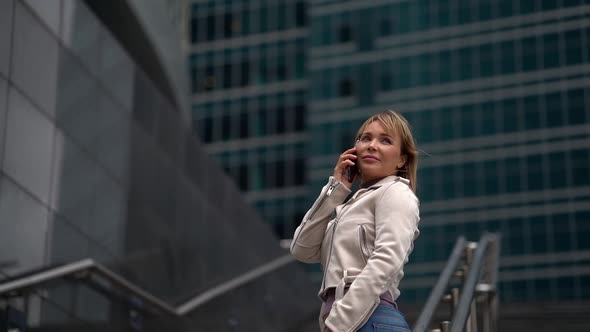 Business Woman Blonde Talking on the Phone Standing on the Stairs in the Background of a Beautiful alt