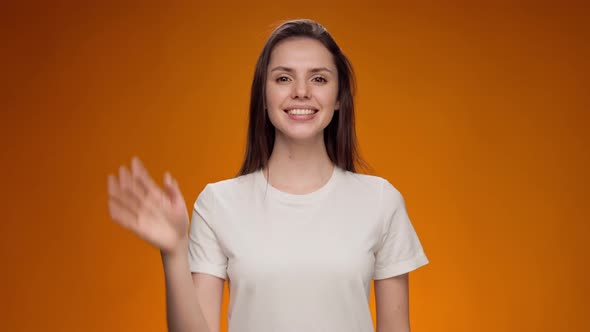 Friendly Young Woman Communicating with Deafmute Sign Language Against Yellow Background alt