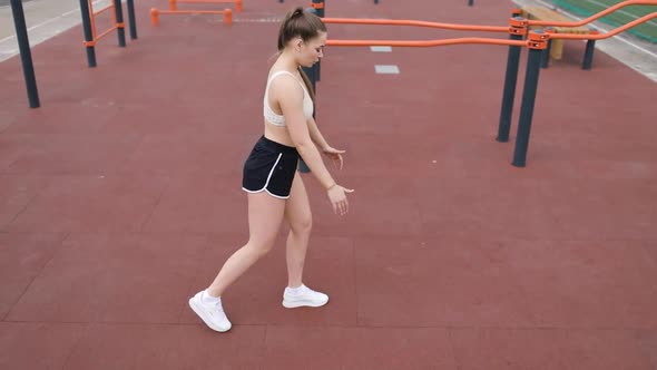 A Beautiful Young Woman in Sportswear is Doing Lunges on the Sports Ground with a Red Sports Floor