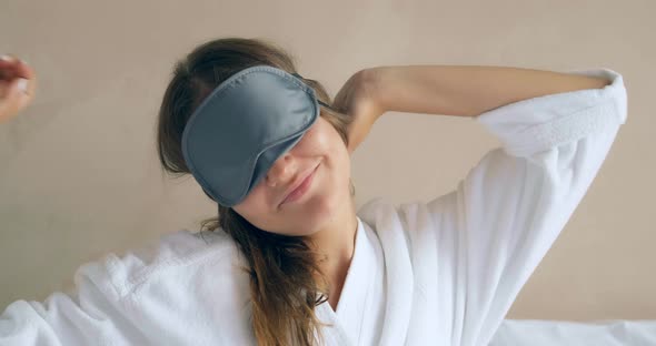 Young Woman Takes Off Black Sleep Mask Sitting By Wall Close