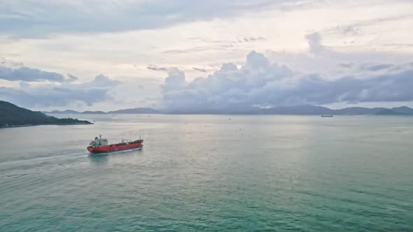 Drone flying towards one industrial ship sailing in sea at sunrise. Chinese cargo ship. alt