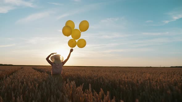 Woman with Balloons in Hand Runs Through a Wheat Field at Sunset alt