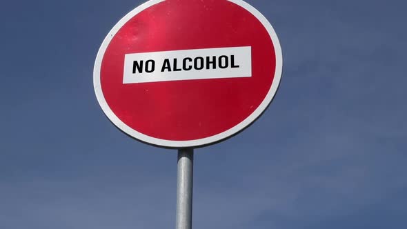 red road sign no entry with text No Alcohol against the blue sky background