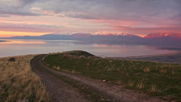Dirt road winding on hilltop during colorful sunset alt