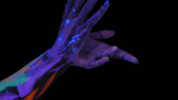 Closeup of a Woman with Ultraviolet Drawings on Her Hands She Moves Her Fingers alt