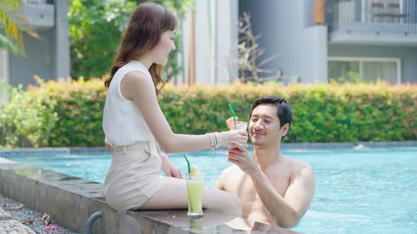 Asian couple lounging by the pool inside the hotel