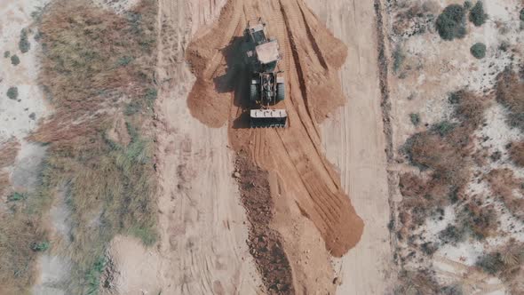 Aerial Top Down View Of Earth Mover Flattening Material On Ground In Pakistan alt