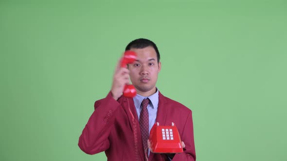 Face of Happy Asian Businessman Using Telephone and Getting Good News alt