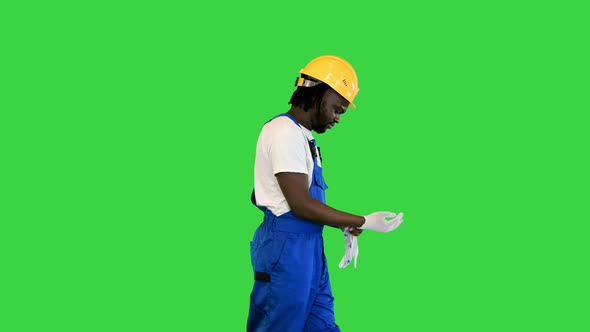 Construction Worker Putting on Gloves While Walking on a Green Screen Chroma Key