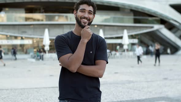 Smiling Curly Guy with Crossed Arms Standing on Street alt