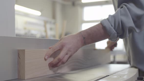 Carpenter Trimming Natural Wood Board on Jointer at Furniture Making Workshop alt