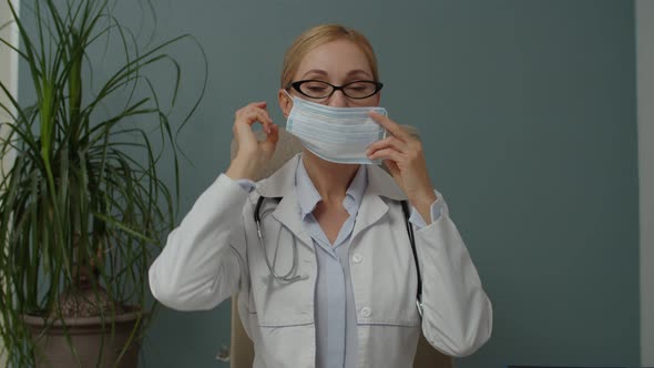 Female Doctor Putting on Face Mask for Protection Coronavirus Indoors alt