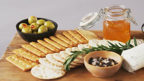 Bowl of green olives, spices, crispy biscuits, jam, rosemary herb, cheese and walnuts alt