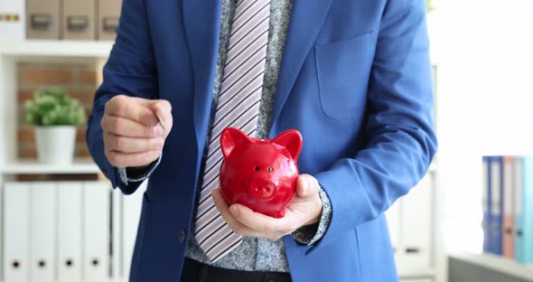 Businessman Tosses Coin Into Piggy Bank  Movie alt