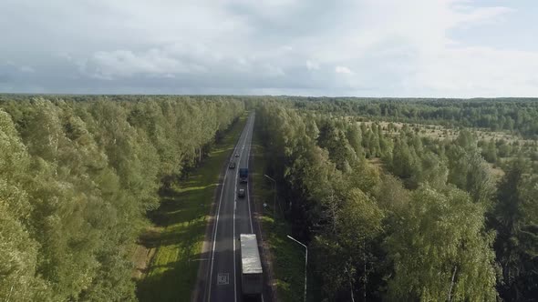 A Busy Highway Surrounded By Trees Along Which Trucks and Cars Drive