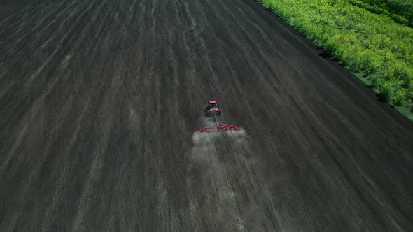 Cultivating Land for Agricultural Crops Using a Tractor. Aerial View of the Sowing Field. View From