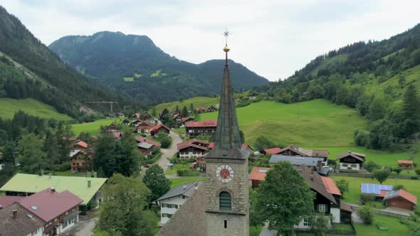 Aerial View of Old Stone Chapel with Clock in Mountain Village in Alps, Germany