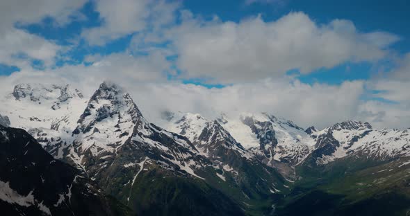 Air Flight Through Mountain Clouds Over Beautiful Snowcapped Peaks of Mountains and Glaciers alt
