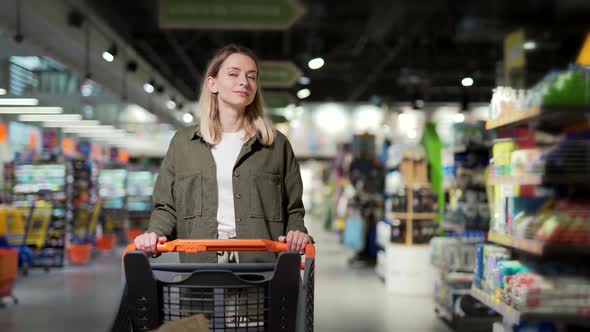 young happy woman pushing trolley spends time in a supermarket or mall store. alt
