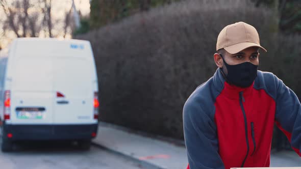 Man with Face Mask Pushing Trolley with Cardboard Boxes alt